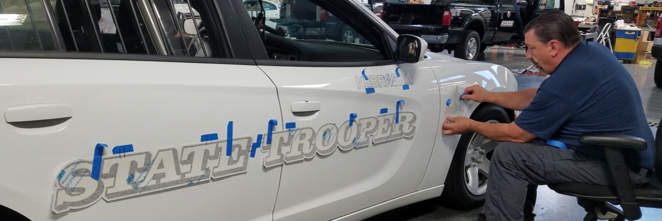 man applying tape to patrol car