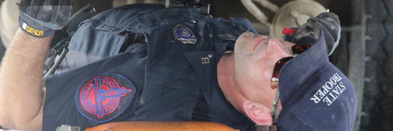 state patrol officer underneath vehicle performing maintenance